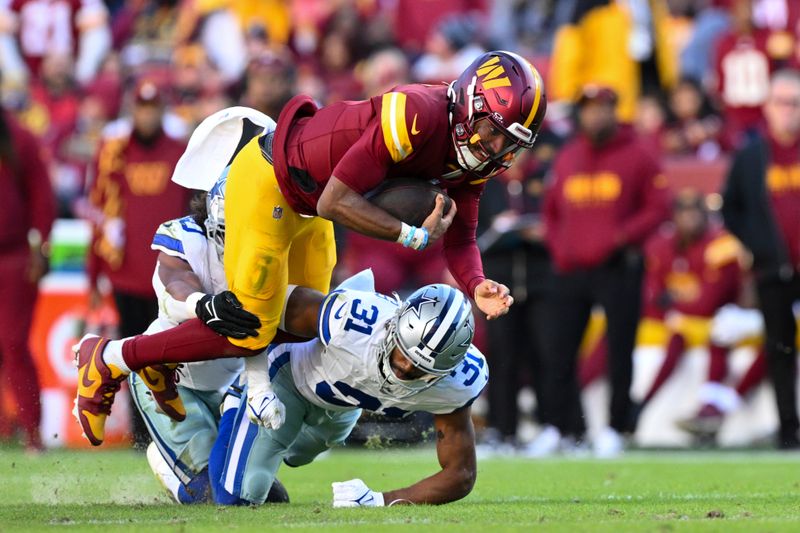 Washington Commanders quarterback Jayden Daniels runs the ball and is tackled by Dallas Cowboys cornerback Josh Butler (31) during the second half of an NFL football game, Sunday, Nov. 24, 2024, in Landover, Md. (AP Photo/Terrance Williams)