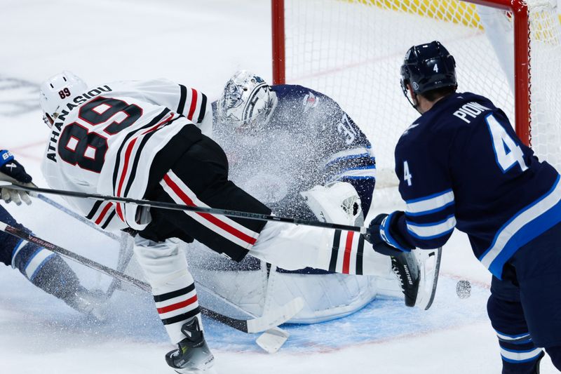 Oct 11, 2024; Winnipeg, Manitoba, CAN;  Winnipeg Jets goalie Connor Hellebuyck (37) stops Chicago Blackhawks forward Andreas Athanasiou (89) during the third period at Canada Life Centre. Mandatory Credit: Terrence Lee-Imagn Images