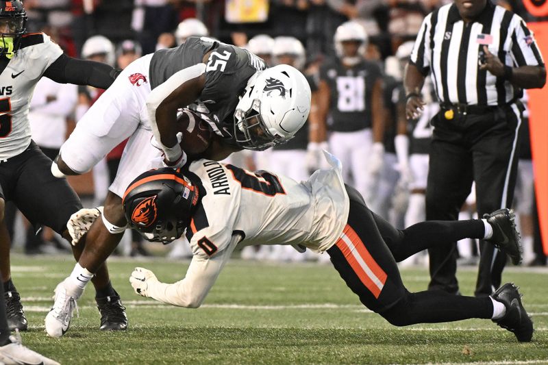 Sep 23, 2023; Pullman, Washington, USA; Washington State Cougars running back Nakia Watson (25) is tackled by Oregon State Beavers defensive back Akili Arnold (0) in the second half at Gesa Field at Martin Stadium. Washington State won 38-35. Mandatory Credit: James Snook-USA TODAY Sports