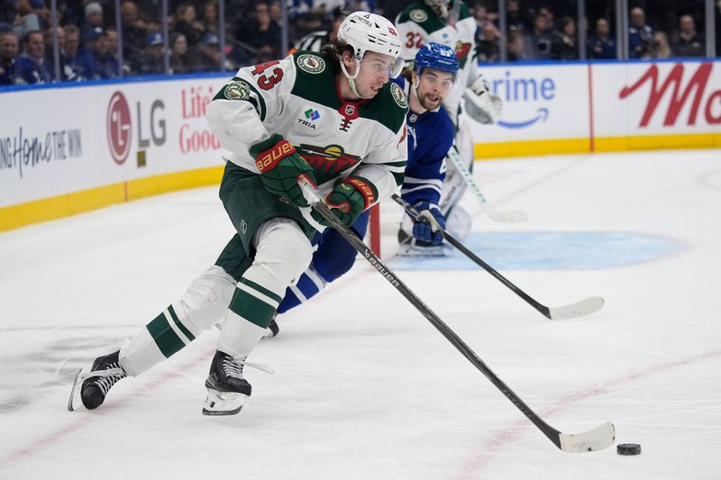 Jan 19, 2026; Toronto, Ontario, CAN; Minnesota Wild defenseman Quinn Hughes (43) plays the puck against Toronto Maple Leafs forward Matias Maccelli (63) during the third period at Scotiabank Arena. Mandatory Credit: John E. Sokolowski-Imagn Images