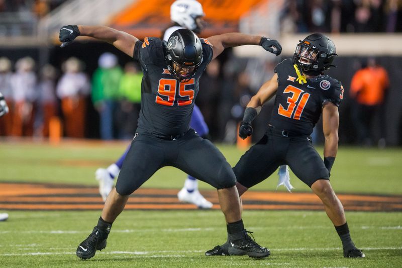 Nov 13, 2021; Stillwater, Oklahoma, USA;  Oklahoma State Cowboys defensive tackle Israel Antwine (95) and safety Kolby Harvell-Peel (31) celebrate after stopping TCU Horned Frogs on a third down during the second quarter at Boone Pickens Stadium. Mandatory Credit: Brett Rojo-USA TODAY Sports