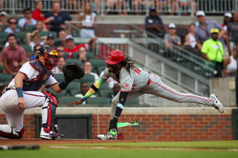 Jul 22, 2024; Atlanta, Georgia, USA; Cincinnati Reds shortstop Elly De La Cruz (44) slides safely past Atlanta Braves catcher Sean Murphy (12) in the first inning at Truist Park. Mandatory Credit: Brett Davis-USA TODAY Sports