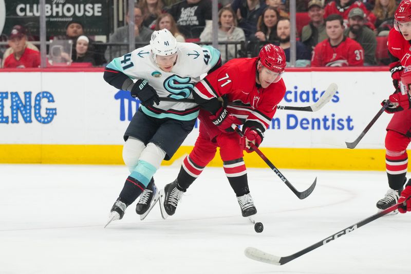 Jan 10, 2026; Raleigh, North Carolina, USA;  Seattle Kraken defenseman Ryker Evans (41) and Carolina Hurricanes left wing Taylor Hall (71) battle over the puck during the first period at Lenovo Center. Mandatory Credit: James Guillory-Imagn Images