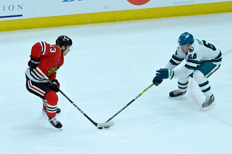 Jan 16, 2024; Chicago, Illinois, USA; Chicago Blackhawks center Philipp Kurashev (23) and San Jose Sharks right wing Mitchell Russell (64) chase the puck during the second period at United Center. Mandatory Credit: Matt Marton-USA TODAY Sports