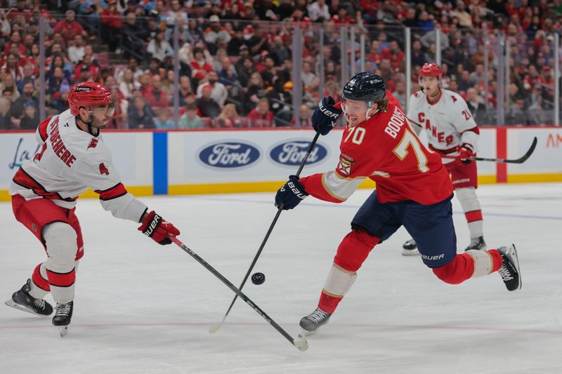 Nov 30, 2024; Sunrise, Florida, USA; Florida Panthers center Jesper Boqvist (70) shoots the puck as Carolina Hurricanes defenseman Shayne Gostisbehere (4) defends during the second period at Amerant Bank Arena. Mandatory Credit: Sam Navarro-Imagn Images