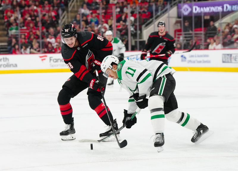 Nov 25, 2024; Raleigh, North Carolina, USA;  Dallas Stars center Logan Stankoven (11) and Carolina Hurricanes center Martin Necas (88) battle over the puck during the second period at Lenovo Center. Mandatory Credit: James Guillory-Imagn Images