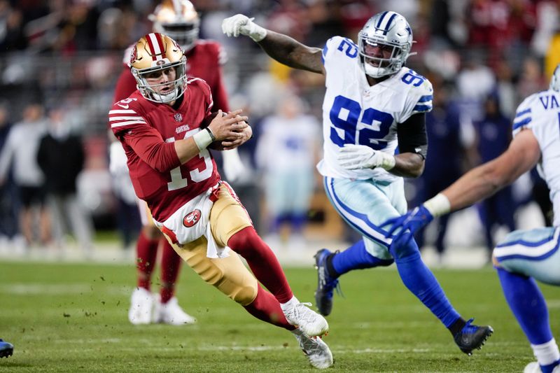 San Francisco 49ers quarterback Brock Purdy (13) runs against Dallas Cowboys defensive end Dorance Armstrong (92) during the second half of an NFL divisional round playoff football game in Santa Clara, Calif., Sunday, Jan. 22, 2023. (AP Photo/Tony Avelar)