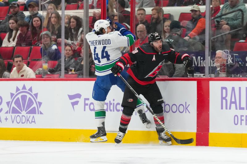 Nov 14, 2025; Raleigh, North Carolina, USA;  Carolina Hurricanes left wing Jordan Martinook (48) checks Vancouver Canucks left wing Kiefer Sherwood (44) during the second period at Lenovo Center. Mandatory Credit: James Guillory-Imagn Images