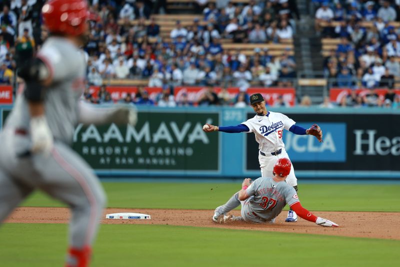 May 17, 2024; Los Angeles, California, USA;  Los Angeles Dodgers shortstop Mookie Betts (50) completes a double-play as he throws the ball over Cincinnati Reds catcher Tyler Stephenson (37) during the second inning at Dodger Stadium. Mandatory Credit: Kiyoshi Mio-USA TODAY Sports