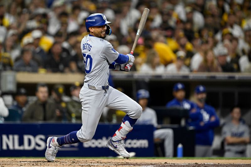 Oct 9, 2024; San Diego, California, USA; Los Angeles Dodgers shortstop Mookie Betts (50) hits a RBI single in the second inning against the San Diego Padres during game four of the NLDS for the 2024 MLB Playoffs at Petco Park.  Mandatory Credit: Denis Poroy-Imagn Images