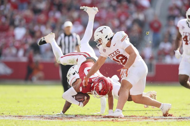 Nov 16, 2024; Fayetteville, Arkansas, USA; Arkansas Razorbacks quarterback Taylen Green (10) is tackled by Texas Longhorns defensive back Jaylon Guilbeau (3) as linebacker Liona Leaf (18) defends during the fourth quarter at Donald W. Reynolds Razorback Stadium. Texas won 20-10. Mandatory Credit: Nelson Chenault-Imagn Images