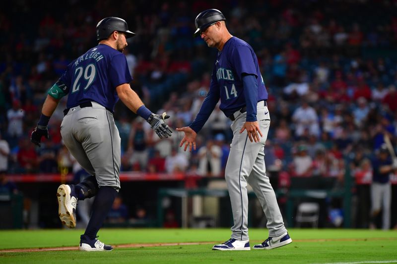 Jul 11, 2024; Anaheim, California, USA; Seattle Mariners catcher Cal Raleigh (29) is greeted by third base coach Manny Acta (14) after hitting a three run home run against the Los Angeles Angels during the sixth inning at Angel Stadium. Mandatory Credit: Gary A. Vasquez-USA TODAY Sports