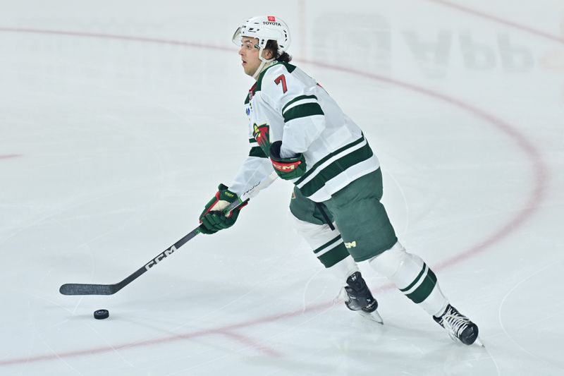 Mar 7, 2024; Tempe, Arizona, USA; Minnesota Wild defenseman Brock Faber (7) looks to pass the puck in the first period against the Arizona Coyotes at Mullett Arena. Mandatory Credit: Matt Kartozian-USA TODAY Sports