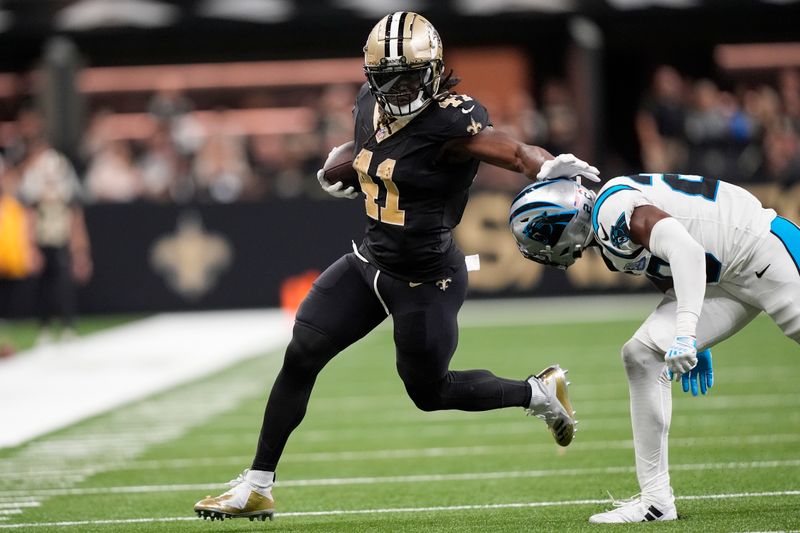 New Orleans Saints running back Alvin Kamara (41) runs the ball past Carolina Panthers safety Jordan Fuller (20) during the second half of an NFL football game Sunday, Sept. 8, 2024, in New Orleans. (AP Photo/Gerald Herbert)