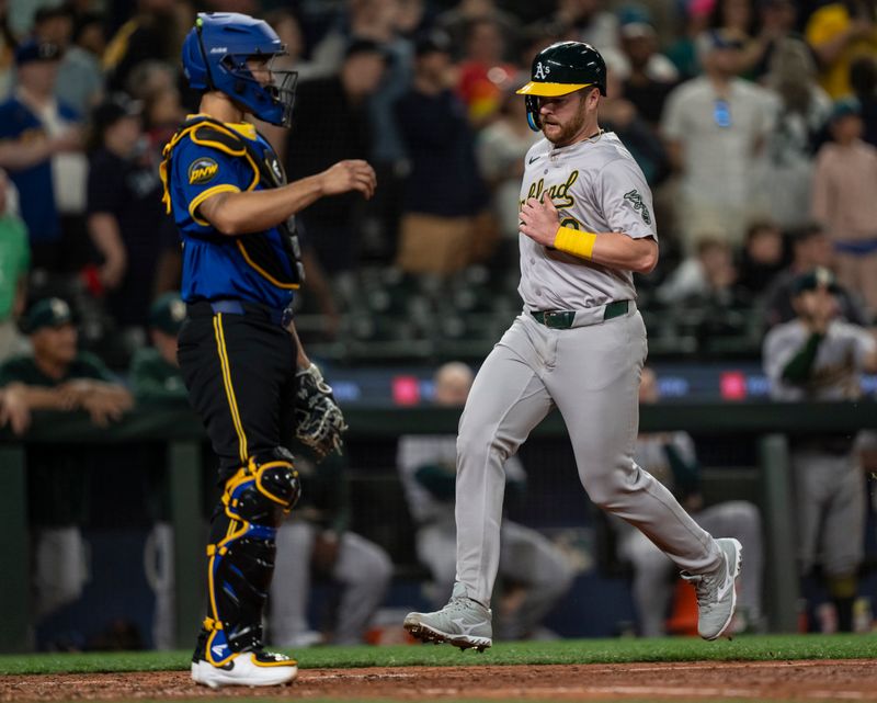 May 10, 2024; Seattle, Washington, USA; Oakland Athletics catcher Kyle McCann (52) scores a run in front of Seattle Mariners catcher Seby Zavala (33) during the ninth inning at T-Mobile Park. Mandatory Credit: Stephen Brashear-USA TODAY Sports