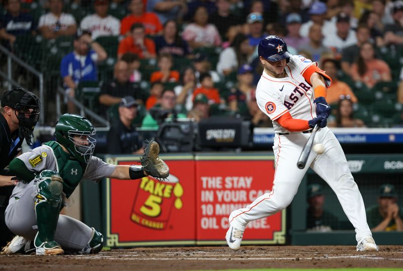 May 27, 2025; Houston, Texas, USA; Houston Astros catcher Yainer Diaz (21) hits a single against the Athletics in the second inning at Daikin Park. Mandatory Credit: Thomas Shea-Imagn Images