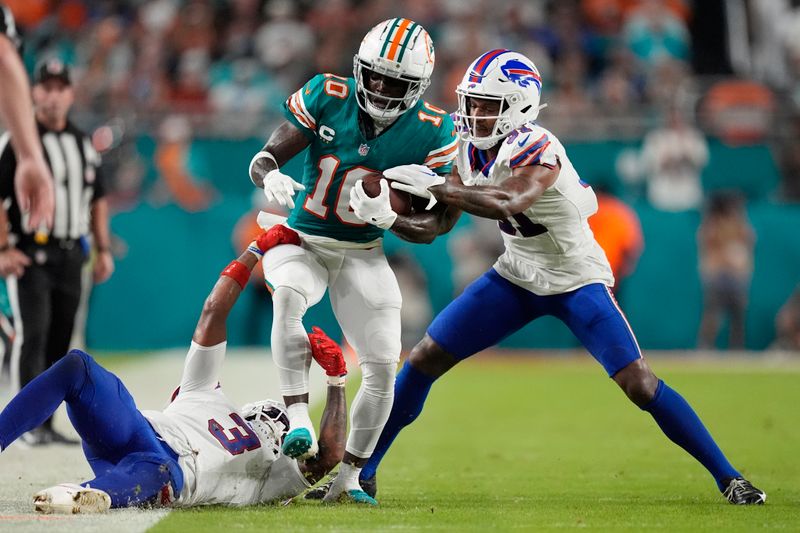 Buffalo Bills cornerback Rasul Douglas (31) and safety Damar Hamlin (3) stop Miami Dolphins wide receiver Tyreek Hill (10) during the first half of an NFL football game, Thursday, Sept. 12, 2024, in Miami Gardens, Fla. (AP Photo/Rebecca Blackwell)