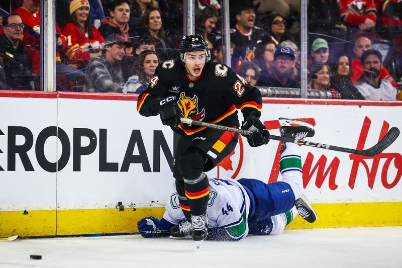 Dec 31, 2024; Calgary, Alberta, CAN; Calgary Flames defenseman Jake Bean (24) and Vancouver Canucks left wing Kiefer Sherwood (44) battles for the puck during the third period at Scotiabank Saddledome. Mandatory Credit: Sergei Belski-Imagn Images