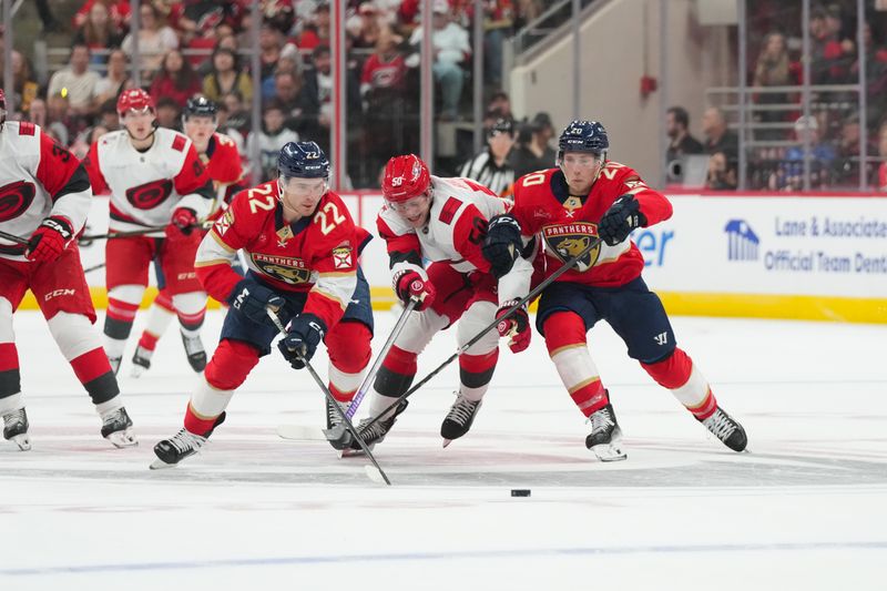 Sep 24, 2025; Raleigh, North Carolina, USA;  Carolina Hurricanes left wing Eric Robinson (50) tries to get to the puck against Florida Panthers defenseman Mike Benning (20) and defenseman Tobias Bjornfot (22) during the first period at Lenovo Center. Mandatory Credit: James Guillory-Imagn Images