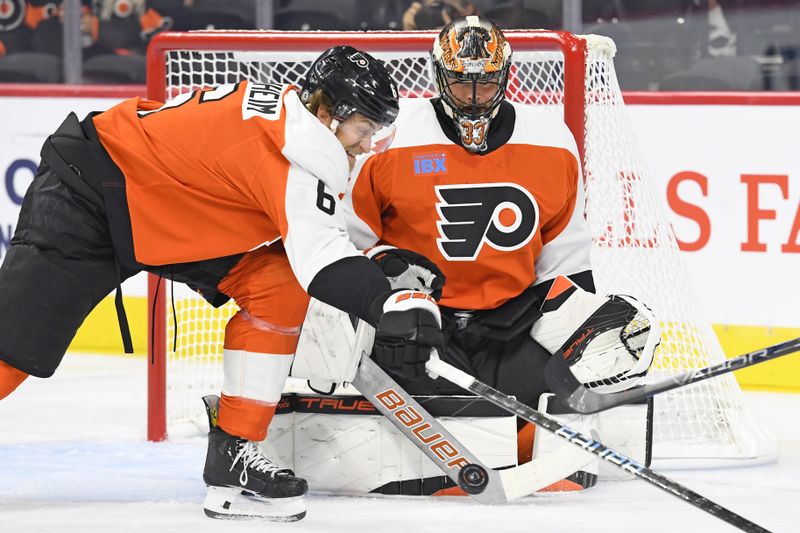 Sep 26, 2024; Philadelphia, Pennsylvania, USA; Philadelphia Flyers goaltender Samuel Ersson (33) makes a save with defenseman Travis Sanheim (6) against the New York Islanders during the first period at Wells Fargo Center. Mandatory Credit: Eric Hartline-Imagn Images