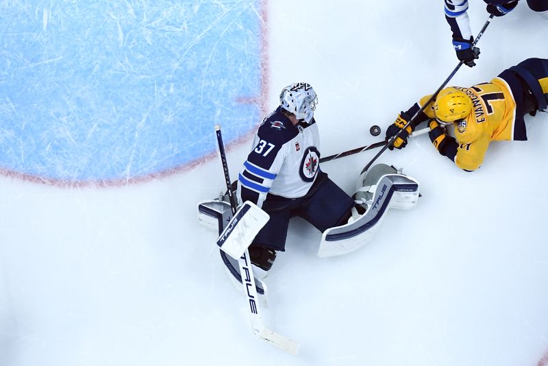 Apr 9, 2024; Nashville, Tennessee, USA; Winnipeg Jets goaltender Connor Hellebuyck (37) stops a shot by Nashville Predators right wing Luke Evangelista (77) during the second period at Bridgestone Arena. Mandatory Credit: Christopher Hanewinckel-USA TODAY Sports