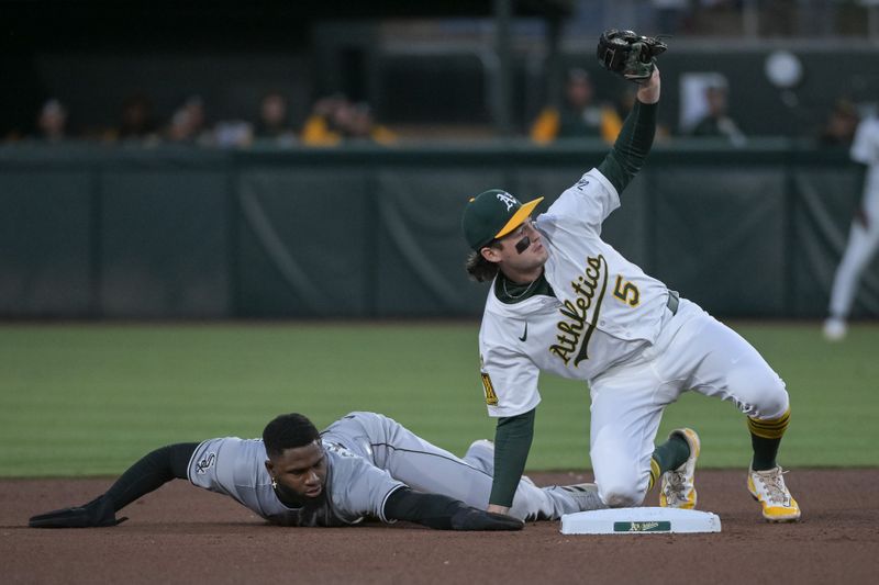 Apr 25, 2025; West Sacramento, California, USA; Athletics shortstop Jacob Wilson (5) tags out Chicago White Sox outfielder Luis Robert Jr. (88) on an attempted steal during the third inning at Sutter Health Park. Mandatory Credit: Ed Szczepanski-Imagn Images