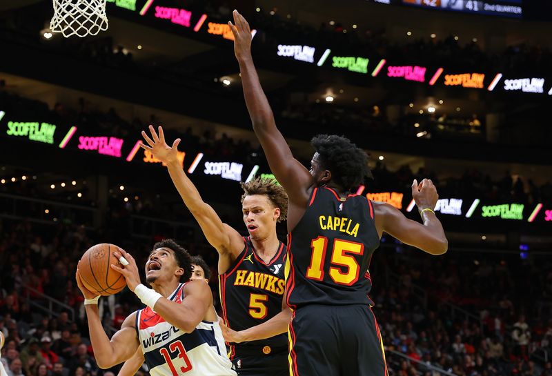 ATLANTA, GEORGIA - NOVEMBER 15:  Jordan Poole #13 of the Washington Wizards attacks the basket against Dyson Daniels #5 and Clint Capela #15 of the Atlanta Hawks during the second quarter of the Emirates NBA Cup game at State Farm Arena on November 15, 2024 in Atlanta, Georgia.  NOTE TO USER: User expressly acknowledges and agrees that, by downloading and/or using this photograph, user is consenting to the terms and conditions of the Getty Images License Agreement.  (Photo by Kevin C. Cox/Getty Images)