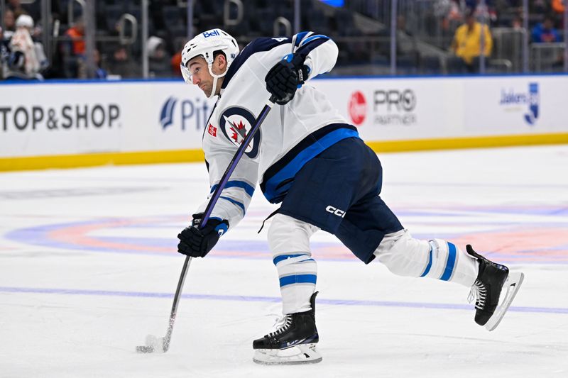 Mar 23, 2024; Elmont, New York, USA;  Winnipeg Jets defenseman Neal Pionk (4) attempts a shot against the New York Islanders during the third period at UBS Arena. Mandatory Credit: Dennis Schneidler-USA TODAY Sports