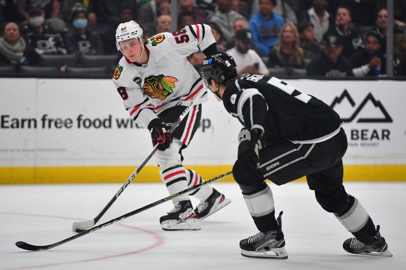 Apr 18, 2024; Los Angeles, California, USA; Chicago Blackhawks right wing MacKenzie Entwistle (58) moves the puck against Los Angeles Kings defenseman Andreas Englund (5) during the first period at Crypto.com Arena. Mandatory Credit: Gary A. Vasquez-USA TODAY Sports