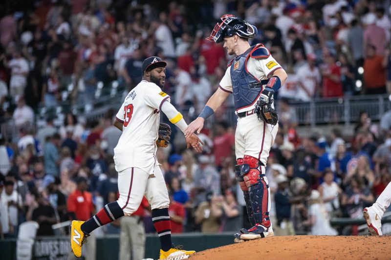 Aug 22, 2024; Cumberland, Georgia, USA; Atlanta Braves outfielder Michael Harris II (23) and catcher Sean Murphy (12) celebrate the end of the game against Philadelphia Phillies with a high-five at Truist Park. Mandatory Credit: Jordan Godfree-USA TODAY Sports