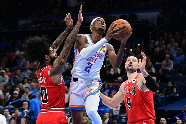 OKLAHOMA CITY, OKLAHOMA - NOVEMBER 22: Shai Gilgeous-Alexander #2 of the Oklahoma City Thunder goes to the basket between Coby White #0 and Nikola Vucevic #9 of the Chicago Bulls during the second half at Paycom Center on November 22, 2023 in Oklahoma City, Oklahoma. NOTE TO USER: User expressly acknowledges and agrees that, by downloading and or using this Photograph, user is consenting to the terms and conditions of the Getty Images License Agreement. (Photo by Joshua Gateley/Getty Images)