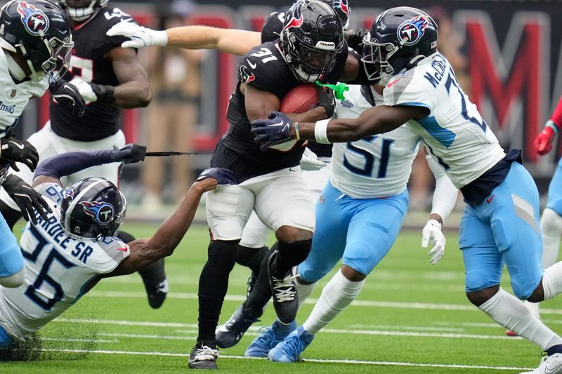 Houston Texans running back Dameon Pierce (31) is tackled by Tennessee Titans cornerbacks Roger McCreary, right, and Justin Hardee Sr. (26) during the first half of an NFL football game Sunday, Nov. 24, 2024, in Houston. (AP Photo/Ashley Landis)