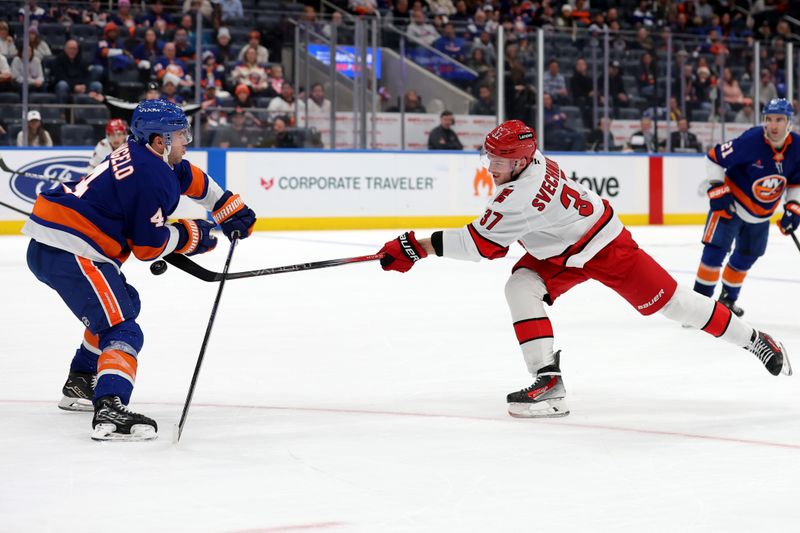 Jan 25, 2025; Elmont, New York, USA; New York Islanders defenseman Tony DeAngelo (4) blocks a shot by Carolina Hurricanes right wing Andrei Svechnikov (37) during overtime at UBS Arena. Mandatory Credit: Brad Penner-Imagn Images