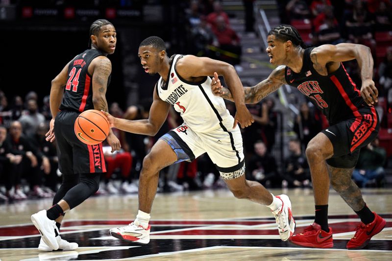 Jan 6, 2024; San Diego, California, USA; San Diego State Aztecs guard Lamont Butler (5) dribbles the ball past UNLV Rebels guard Luis Rodriguez (15) and guard Jackie Johnson III (24) during the second half at Viejas Arena. Mandatory Credit: Orlando Ramirez-USA TODAY Sports