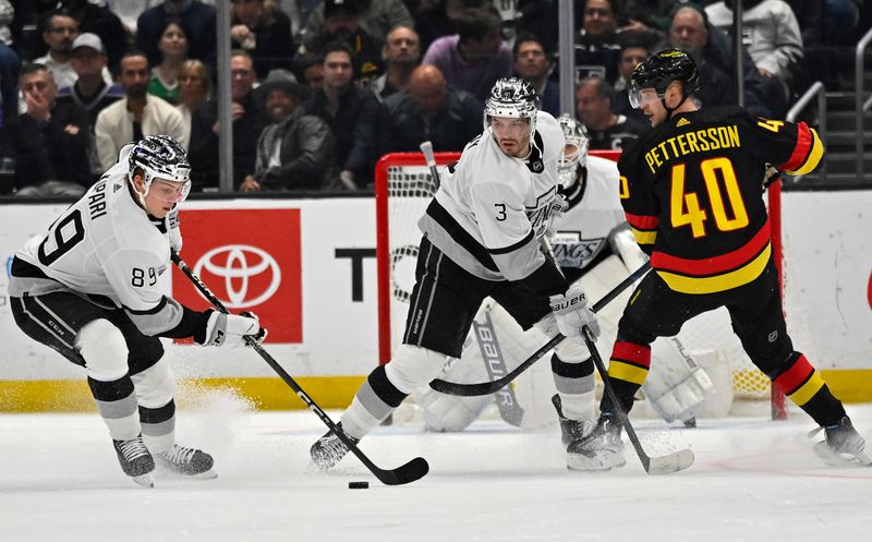 Apr 10, 2023; Los Angeles, California, USA;  Los Angeles Kings defenseman Matt Roy (3) and Vancouver Canucks center Elias Pettersson (40) hold their position as center Rasmus Kupari (89) clears the puck in the second period at Crypto.com Arena. Mandatory Credit: Jayne Kamin-Oncea-USA TODAY Sports