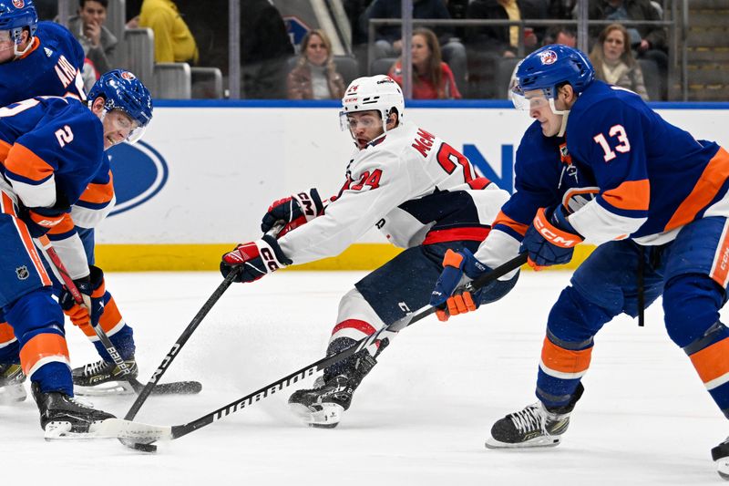 Dec 29, 2023; Elmont, New York, USA; Washington Capitals center Connor McMichael (24) attempts a shot defended by New York Islanders center Mathew Barzal (13) during the third period at UBS Arena. Mandatory Credit: Dennis Schneidler-USA TODAY Sports