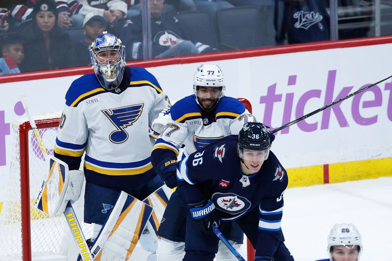 Dec 3, 2024; Winnipeg, Manitoba, CAN;  Winnipeg Jets forward Morgan Barron (36) jostles for position with St. Louis Blues defenseman Pierre-Olivier Joseph (77) in front of St. Louis Blues goalie Joel Hofer (30) during the third period at Canada Life Centre. Mandatory Credit: Terrence Lee-Imagn Images