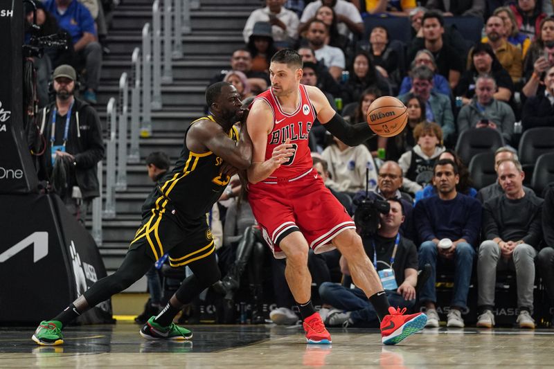 SAN FRANCISCO, CA - MARCH 07: Nikola Vucevic #9 of the Chicago Bulls dribbles the ball in the second quarter against Draymond Green #23 of the Golden State Warriors at Chase Center on March 7, 2024 in San Francisco, California. NOTE TO USER: User expressly acknowledges and agrees that, by downloading and/or using this photograph, User is consenting to the terms and conditions of the Getty Images License Agreement. (Photo by Kavin Mistry/Getty Images)