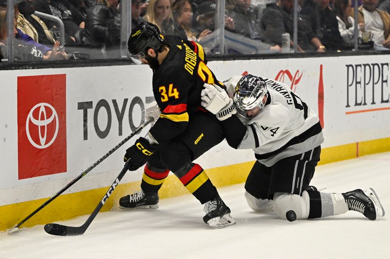 Apr 10, 2023; Los Angeles, California, USA;  Vancouver Canucks left wing Phillip Di Giuseppe (34) and Los Angeles Kings defenseman Vladislav Gavrikov (84) battle along the boards in the first period at Crypto.com Arena. Mandatory Credit: Jayne Kamin-Oncea-USA TODAY Sports