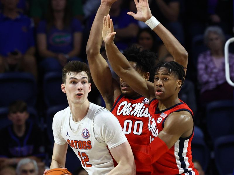 Feb 15, 2023; Gainesville, Florida, USA;  Florida Gators forward Colin Castleton (12) passes the ball as Mississippi Rebels guard Matthew Murrell (11) and Mississippi Rebels forward Jayveous McKinnis (00) defend during the first half at Exactech Arena at the Stephen C. O'Connell Center. Mandatory Credit: Kim Klement-USA TODAY Sports