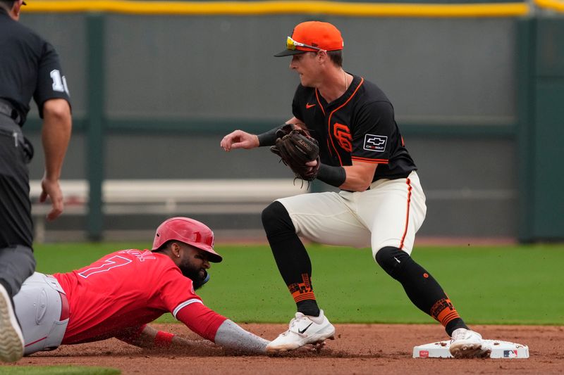 Feb 26, 2024; Scottsdale, Arizona, USA; Los Angeles Angels right fielder Jo Adell (7) dives back safely under the tag by San Francisco Giants shortstop Tyler Fitzgerald (49) in the first inning at Scottsdale Stadium. Mandatory Credit: Rick Scuteri-USA TODAY Sports