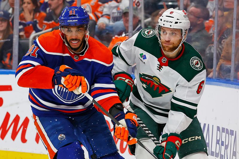 Feb 23, 2024; Edmonton, Alberta, CAN; Edmonton Oilers forward Evander Kane (91) and Minnesota Wild defensemen Dakota Mermis (6) look for a loose puck during the third period at Rogers Place. Mandatory Credit: Perry Nelson-USA TODAY Sports