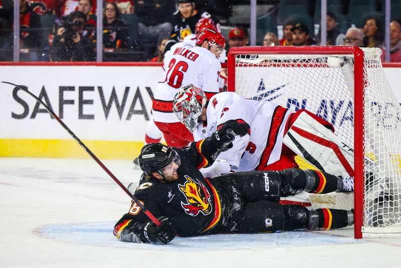 Oct 24, 2024; Calgary, Alberta, CAN; Calgary Flames center Justin Kirkland (58) and Carolina Hurricanes goaltender Pyotr Kochetkov (52) collides during the third period at Scotiabank Saddledome. Mandatory Credit: Sergei Belski-Imagn Images