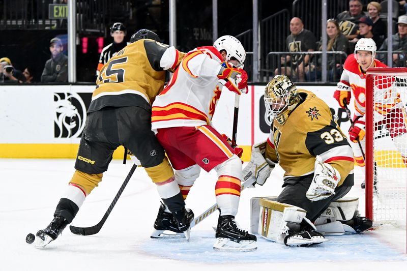 Oct 28, 2024; Las Vegas, Nevada, USA; Vegas Golden Knights defenseman Noah Hanifin (15) stops a shot with his skate near goaltender Adin Hill (33) and Calgary Flames center Blake Coleman (20) in the third period at T-Mobile Arena. Mandatory Credit: Candice Ward-Imagn Images