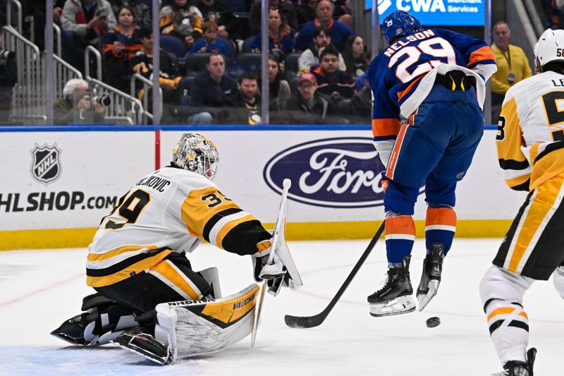 Apr 17, 2024; Elmont, New York, USA;  New York Islanders center Brock Nelson (29) jumps out of the way of the puck in front of Pittsburgh Penguins goaltender Alex Nedeljkovic (39) during the second period at UBS Arena. Mandatory Credit: Dennis Schneidler-USA TODAY Sports