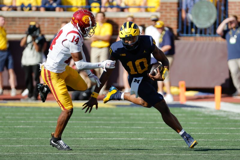 Sep 21, 2024; Ann Arbor, Michigan, USA;  Michigan Wolverines quarterback Alex Orji (10) rushes chased by USC Trojans cornerback Jacobe Covington (14) in the first half at Michigan Stadium. Mandatory Credit: Rick Osentoski-Imagn Images