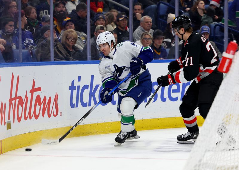 Nov 29, 2024; Buffalo, New York, USA;  Vancouver Canucks right wing Conor Garland (8) clears the puck behind the net as Buffalo Sabres center Ryan McLeod (71) defends during the first period at KeyBank Center. Mandatory Credit: Timothy T. Ludwig-Imagn Images