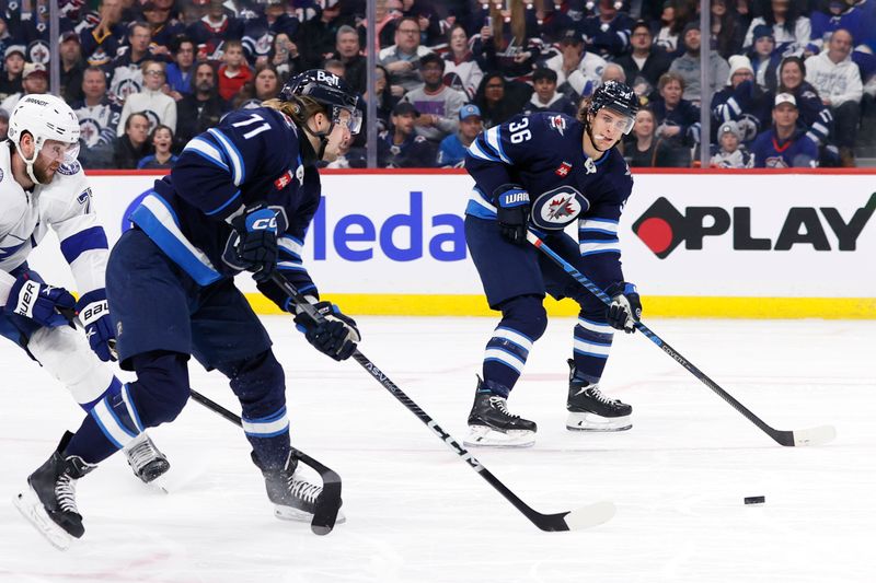 Jan 2, 2024; Winnipeg, Manitoba, CAN; Winnipeg Jets left wing Axel Jonsson-Fjallby (71) passes the puck to Winnipeg Jets center Morgan Barron (36) in the second period against the Tampa Bay Lightning at Canada Life Centre. Mandatory Credit: James Carey Lauder-USA TODAY Sports