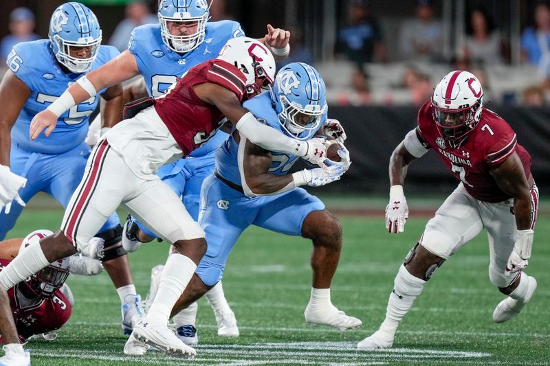 Sep 2, 2023; Charlotte, North Carolina, USA;  North Carolina Tar Heels running back British Brooks (24) runs with South Carolina Gamecocks defensive back B.J. Gibson (36) in pursuiit during the first quarter at Bank of America Stadium. Mandatory Credit: Jim Dedmon-USA TODAY Sports