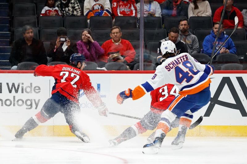 Oct 31, 2025; Washington, District of Columbia, USA; Washington Capitals right wing Brandon Duhaime (22) and Capitals right wing Justin Sourdif (34) chase the puck in front of New York Islanders defenseman Matthew Schaefer (48) during the first period at Capital One Arena. Mandatory Credit: Geoff Burke-Imagn Images
